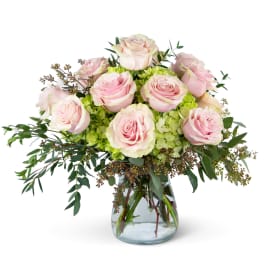 Pink roses arranged in a clear glass vase with green filler