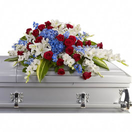 Red roses, white lilies, and blue flowers arranged on a silver casket