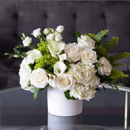 White roses and calla lilies in a white vase
