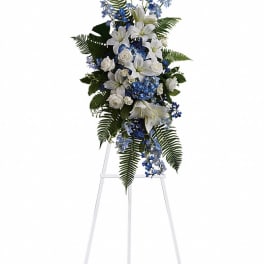 White lilies and blue flowers in a standing spray on an easel