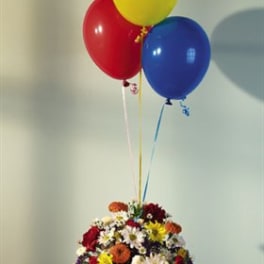Basket of mixed flowers with red, yellow, and blue balloons