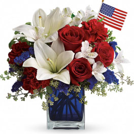 Red roses and white lilies in a blue vase with a small American flag