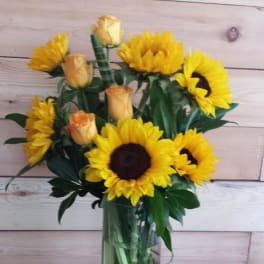 Bouquet of yellow sunflowers and peach roses in a glass vase
