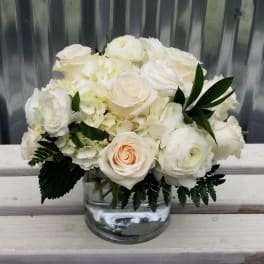 White roses and hydrangeas in a clear glass vase