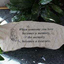 Memorial stone with an engraved sympathy quote surrounded by plants