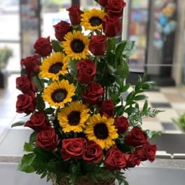 Basket arrangement of red roses and sunflowers