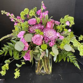 Pink mixed bouquet in a clear glass vase with green accents