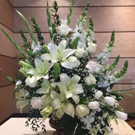 White lilies and roses arranged in a tall vase centerpiece