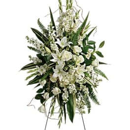 White floral standing spray on an easel with lilies and roses