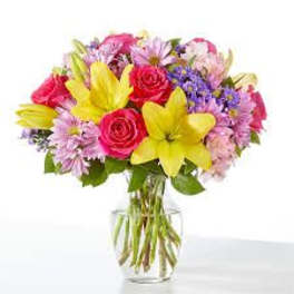 Bouquet of pink roses and yellow lilies in a clear glass vase