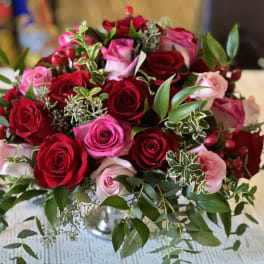 Bouquet of red and pink roses with greenery in a glass vase