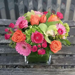 Mixed pink and orange bouquet in a clear square vase