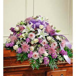 Lavender and white floral casket spray with a purple ribbon
