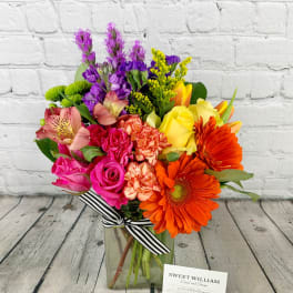 Colorful mixed bouquet in a glass vase with a striped ribbon