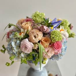 Pastel bouquet of roses, hydrangeas, and mixed blooms in a white vase