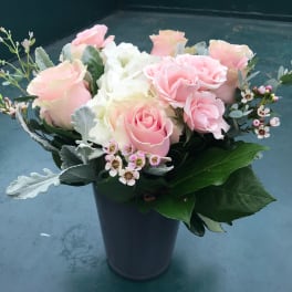 Pink and white roses arranged in a dark vase