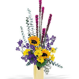 Tall bouquet of sunflowers and purple flowers in a yellow vase