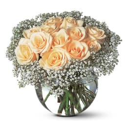Peach roses in a round glass vase with baby's breath