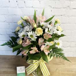Bouquet of pink alstroemeria, white daisies, and yellow carnations in a glass vase