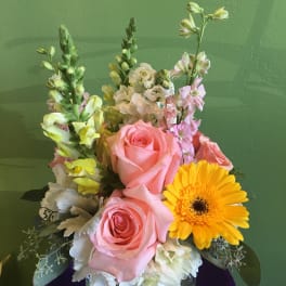 Pink roses and a yellow gerbera daisy in a glass vase