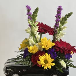 Colorful flower arrangement in a black toy car container