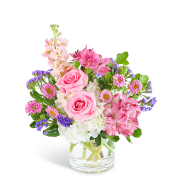 Pink roses and mixed flowers arranged in a clear glass vase