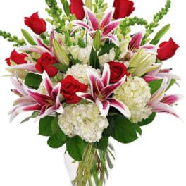 Bouquet of red roses, pink lilies, and white hydrangeas in a glass vase