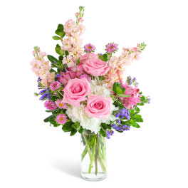 Pink roses and mixed flowers arranged in a clear glass vase