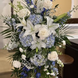Tall blue and white floral spray with roses, lilies, and hydrangeas
