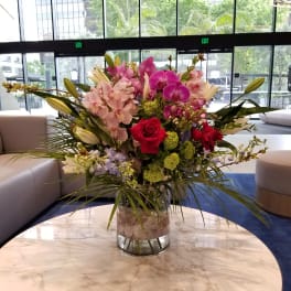 Large mixed bouquet in a clear glass vase with pink orchids and red roses