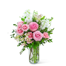 Pink roses and white flowers arranged in a clear glass vase