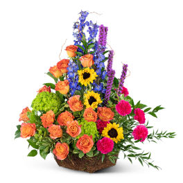 Mixed bouquet with orange roses, sunflowers, blue delphinium, and pink carnations in a basket