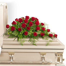 Red rose spray on a white casket