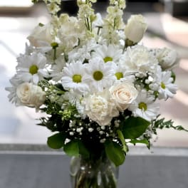 White bouquet of daisies and roses in a clear glass vase