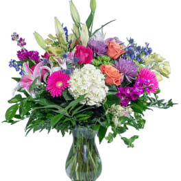 Mixed bouquet of lilies, roses, and daisies in a glass vase