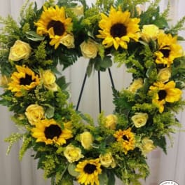 Standing wreath of yellow sunflowers and pale yellow roses on a metal easel