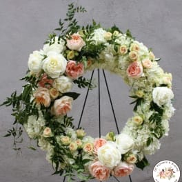 Standing wreath of white and peach roses and hydrangeas on a metal easel