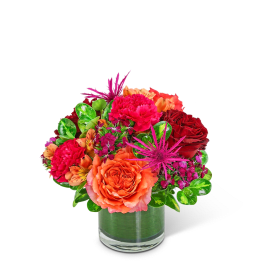 Bright mixed bouquet in a clear glass vase with orange and red blooms
