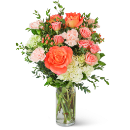 Coral and pink roses with carnations in a clear glass vase