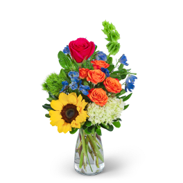 Mixed bouquet in a clear glass vase with roses, sunflower, and blue flowers