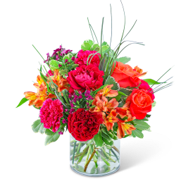Bright mixed bouquet of roses, carnations, and alstroemeria in a glass vase