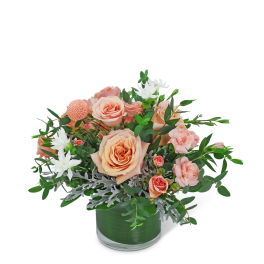 Peach roses and white flowers in a green glass vase
