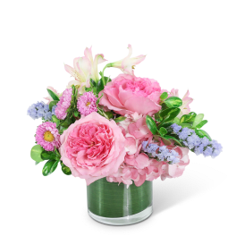 Pink floral arrangement in a clear glass vase with lavender accents