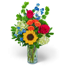 Mixed bouquet with sunflowers, roses, and blue flowers in a glass vase