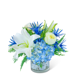 White lilies and blue hydrangeas in a glass vase