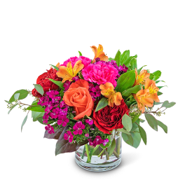Bouquet of red and orange roses with pink flowers in a clear glass vase
