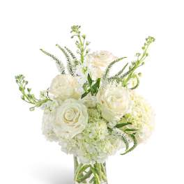 White roses and hydrangeas in a clear glass vase