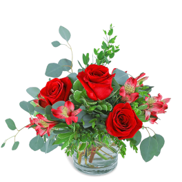 Red roses and pink alstroemeria in a clear glass vase