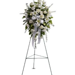 White floral standing spray on an easel with ribbon streamers