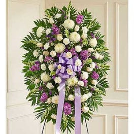 Standing funeral spray of white and purple flowers with a lavender ribbon